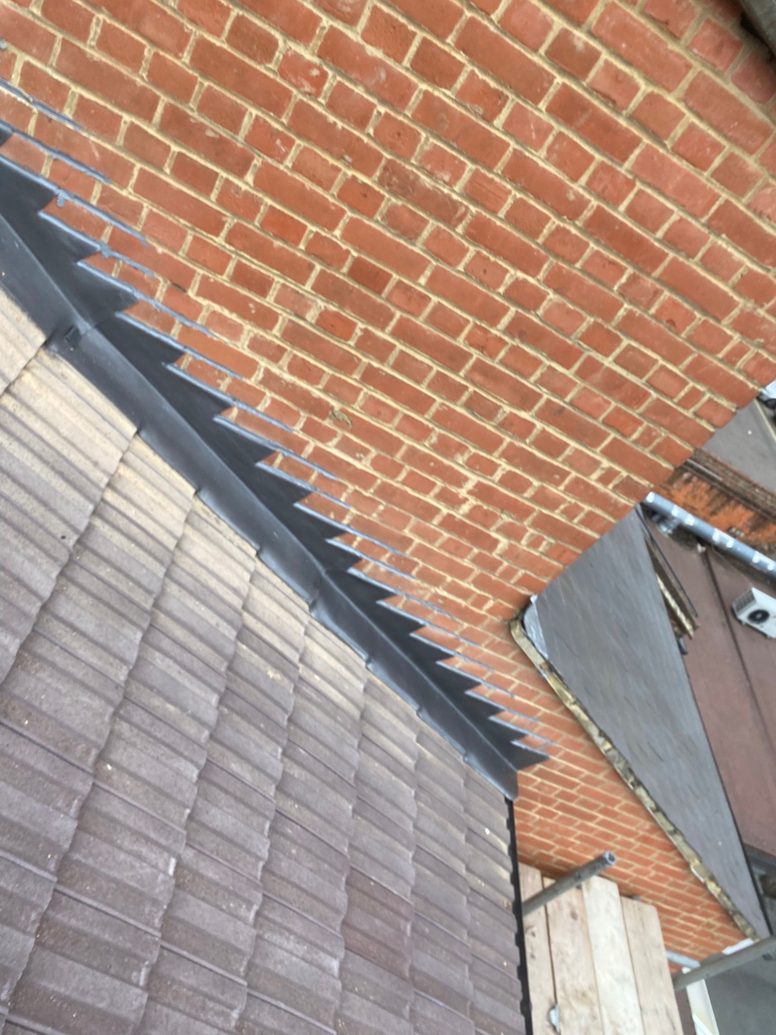 Lead step flashing against brick chimney
